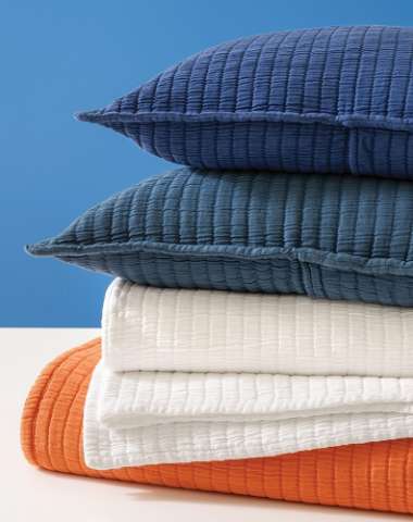 Close up of different color towels and pillows stacked on top of each other