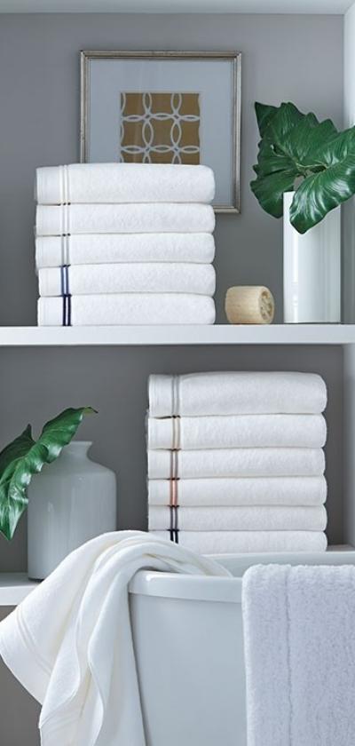 Shelf with towels stacked up, plants and a framed picture