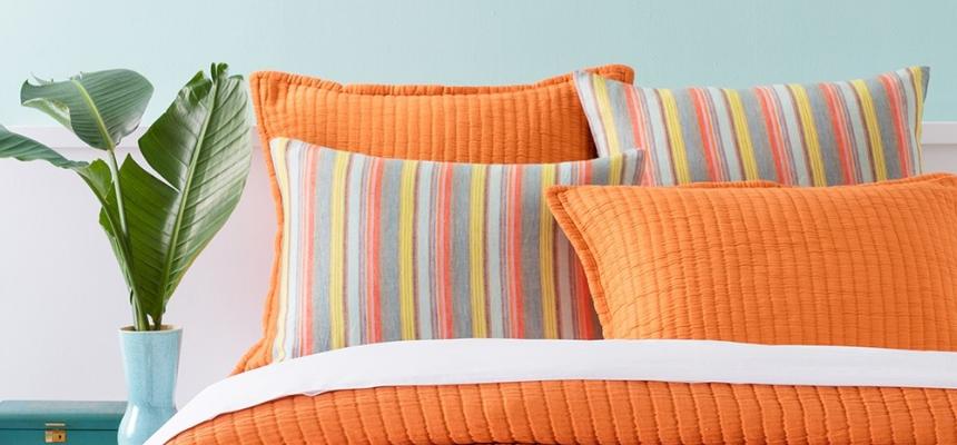 Wide angle shot of a bed with orange throw pillows